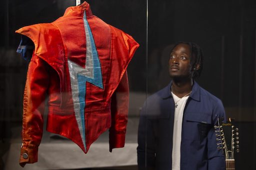 A visitor looks at the Aladdin Sane jacket designed by Freddie Burretti for David Bowie on the Ziggy Stardust live tour in 1973 2048x1366